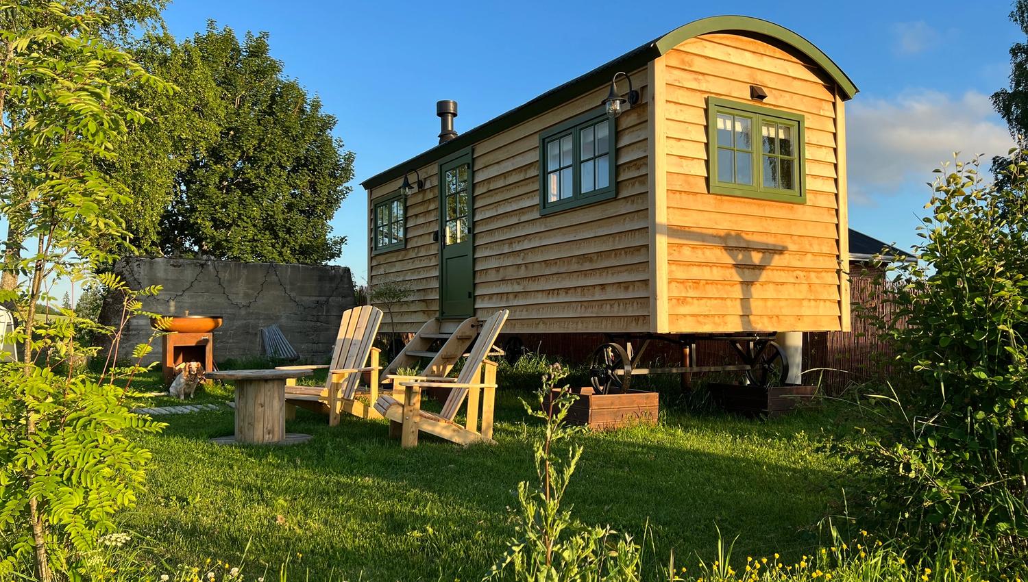 Shepherd's Hut summerday - small hut with green gras and wooden chairs in front