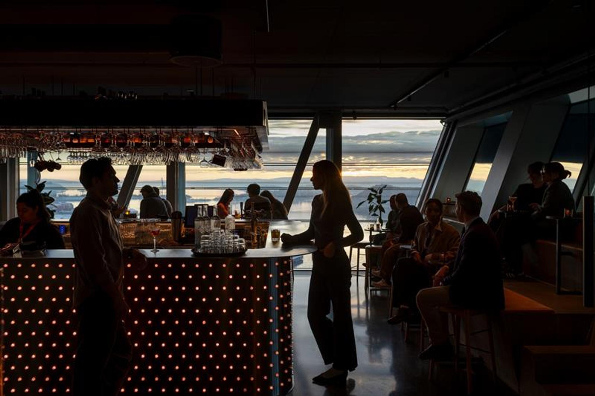 People in a bar with large panoramic windows facing the Oslofjord