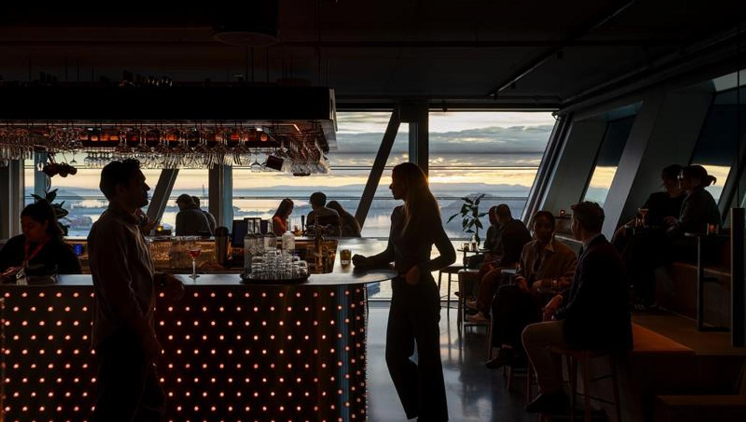 People in a bar with large panoramic windows facing the Oslofjord