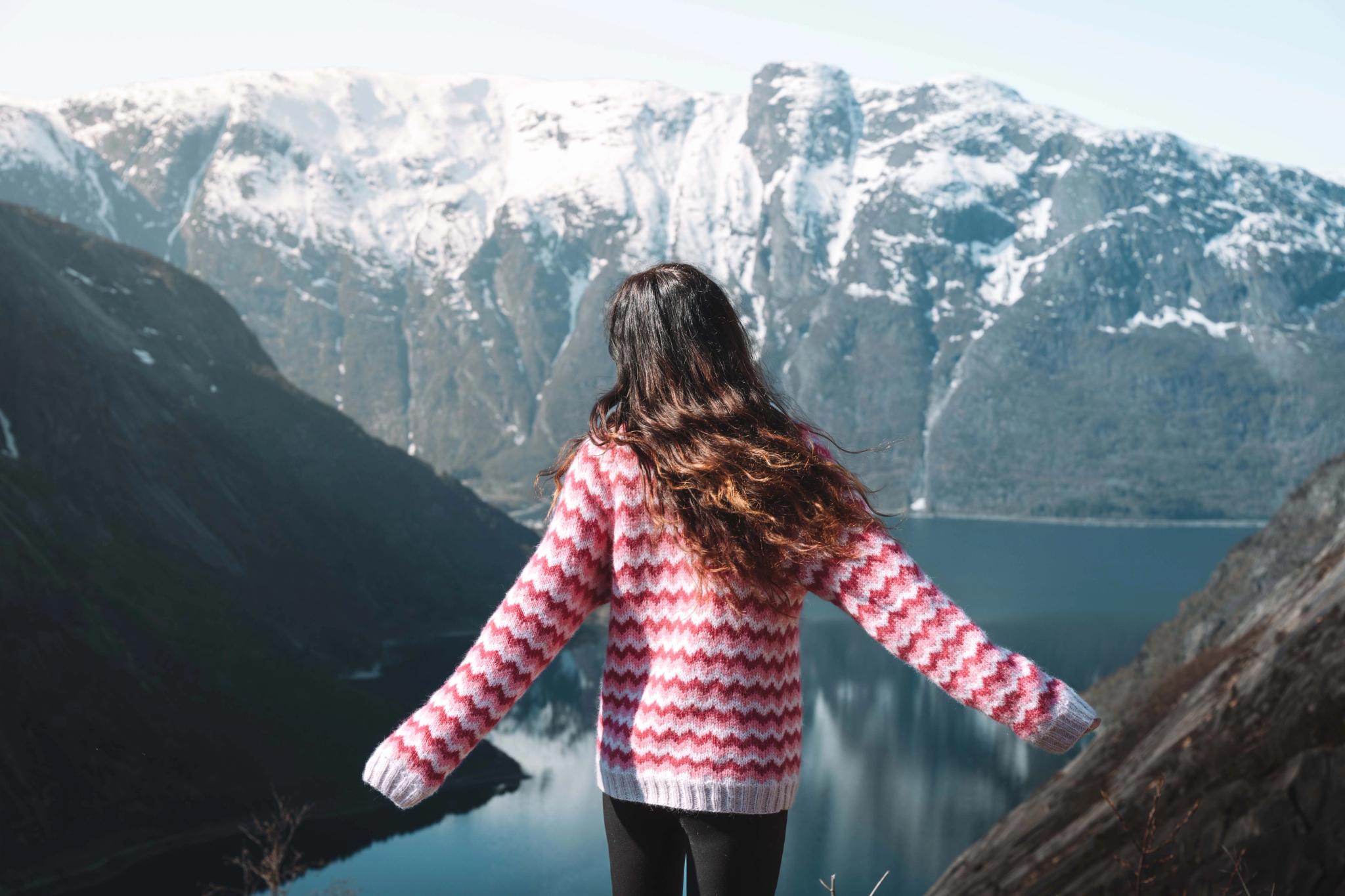 A woman in a pink sweather and long dark hair standing on the Kjeåsen view point.