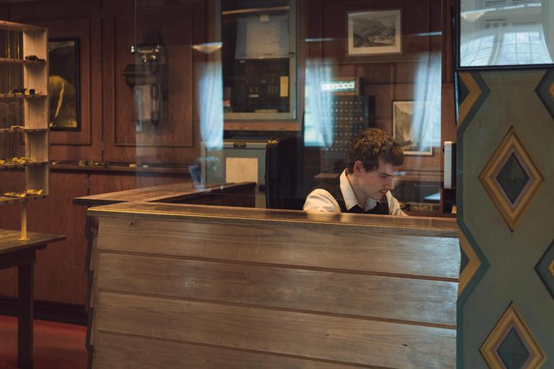 A receptionist sitting behind a glass window working at the fron desk.
