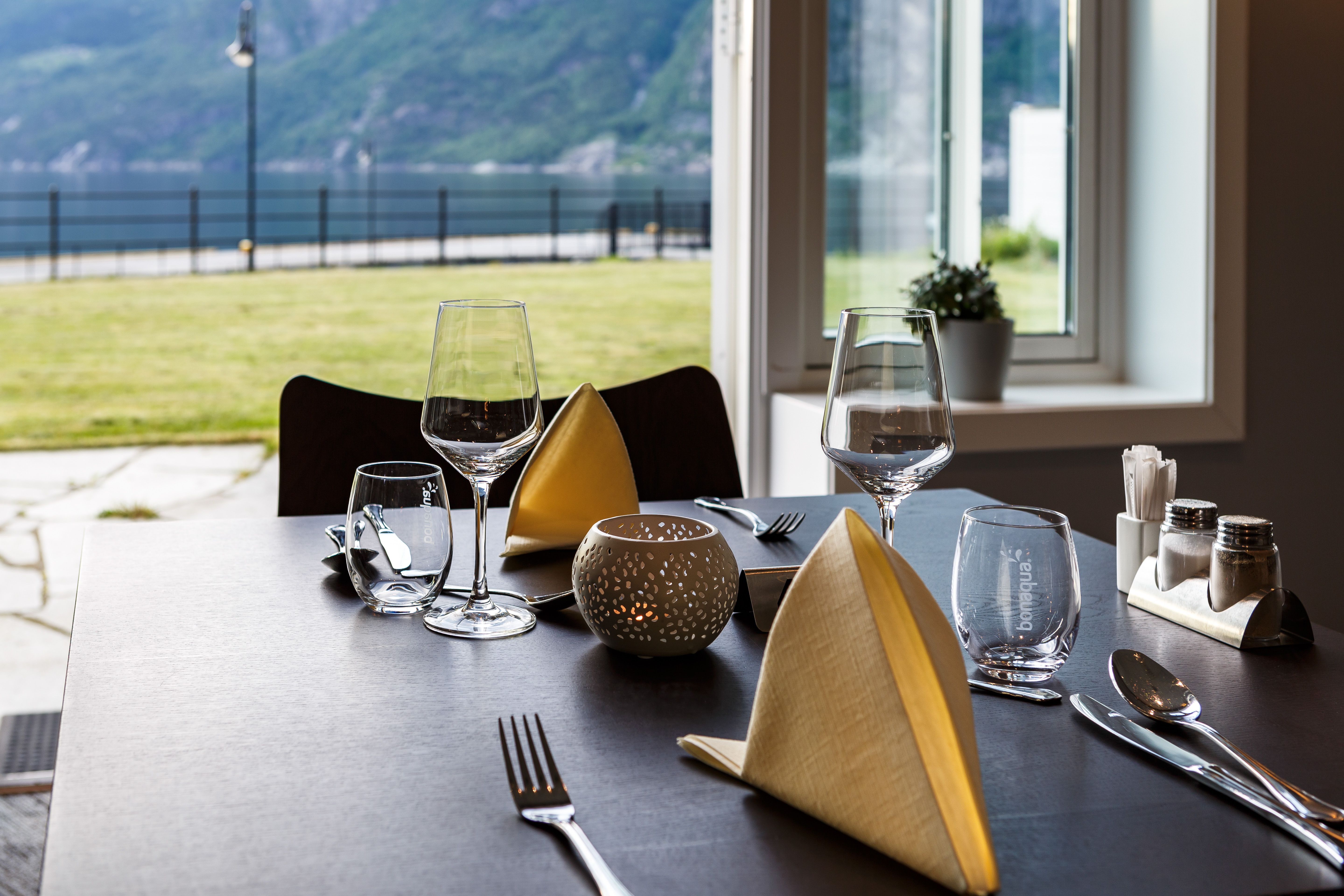 A set table in the restaurant, with a fjord view.