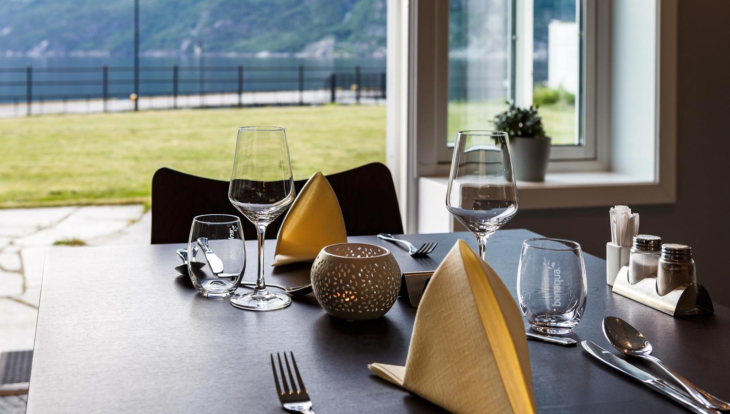 A set table in the restaurant, with a fjord view.