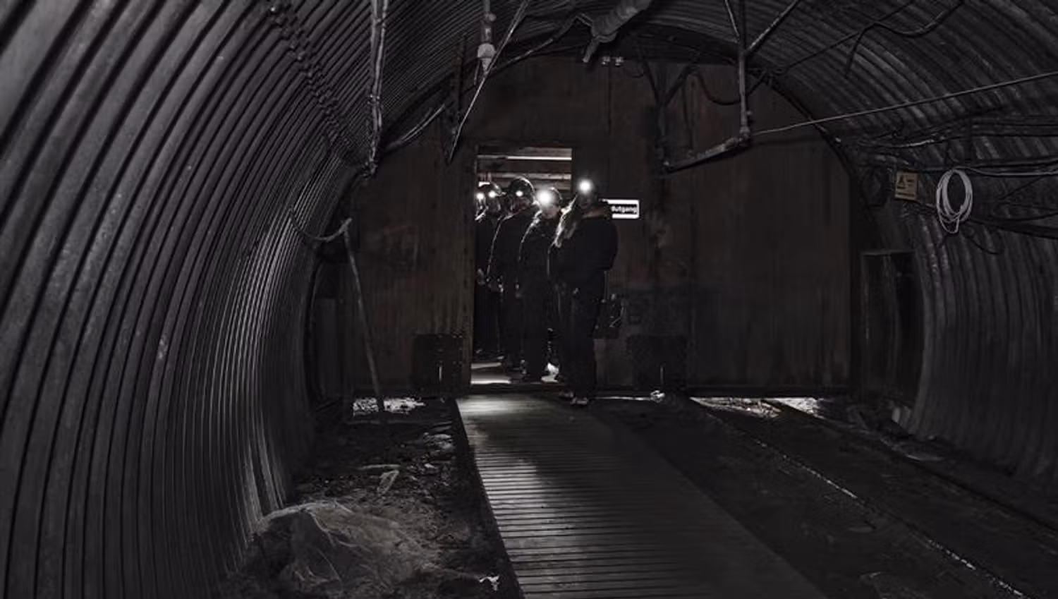 A group of guests with head lamps and helmets on, walking through a mine passage on a guided tour