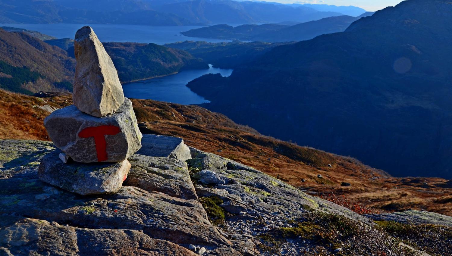 Red-marked trail cairn overlooking Fitjadalen and the dramatic Hardanger fjord landscape.