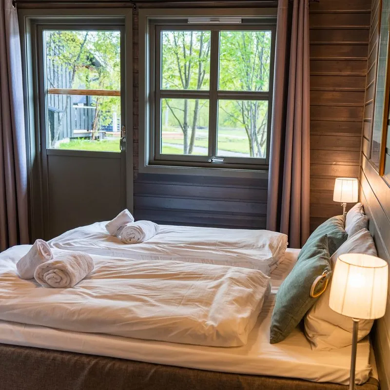 Cozy bedroom with twin beds, window view of trees, and soft lighting.