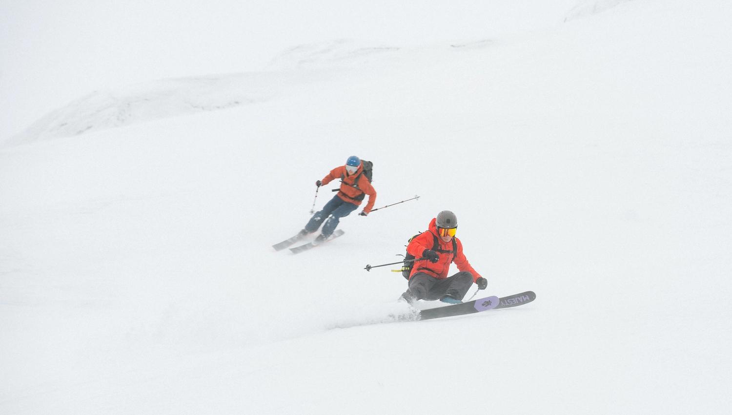 Two men speed skiing down a slope.