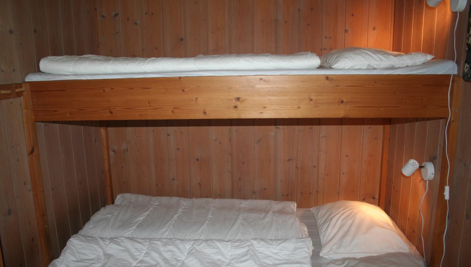 Cozy bedroom with bunk bed and wooden interior in a cabin at Hardanger Feriesenter.