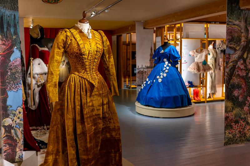 Museum exhibition displaying historic costumes and stage garments in open gallery spaces with accompanying text and illustrations.