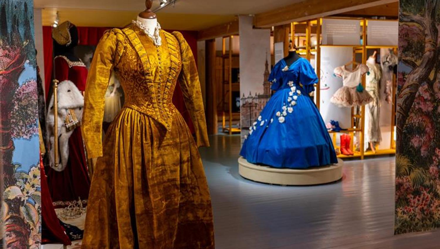 Museum exhibition displaying historic costumes and stage garments in open gallery spaces with accompanying text and illustrations.