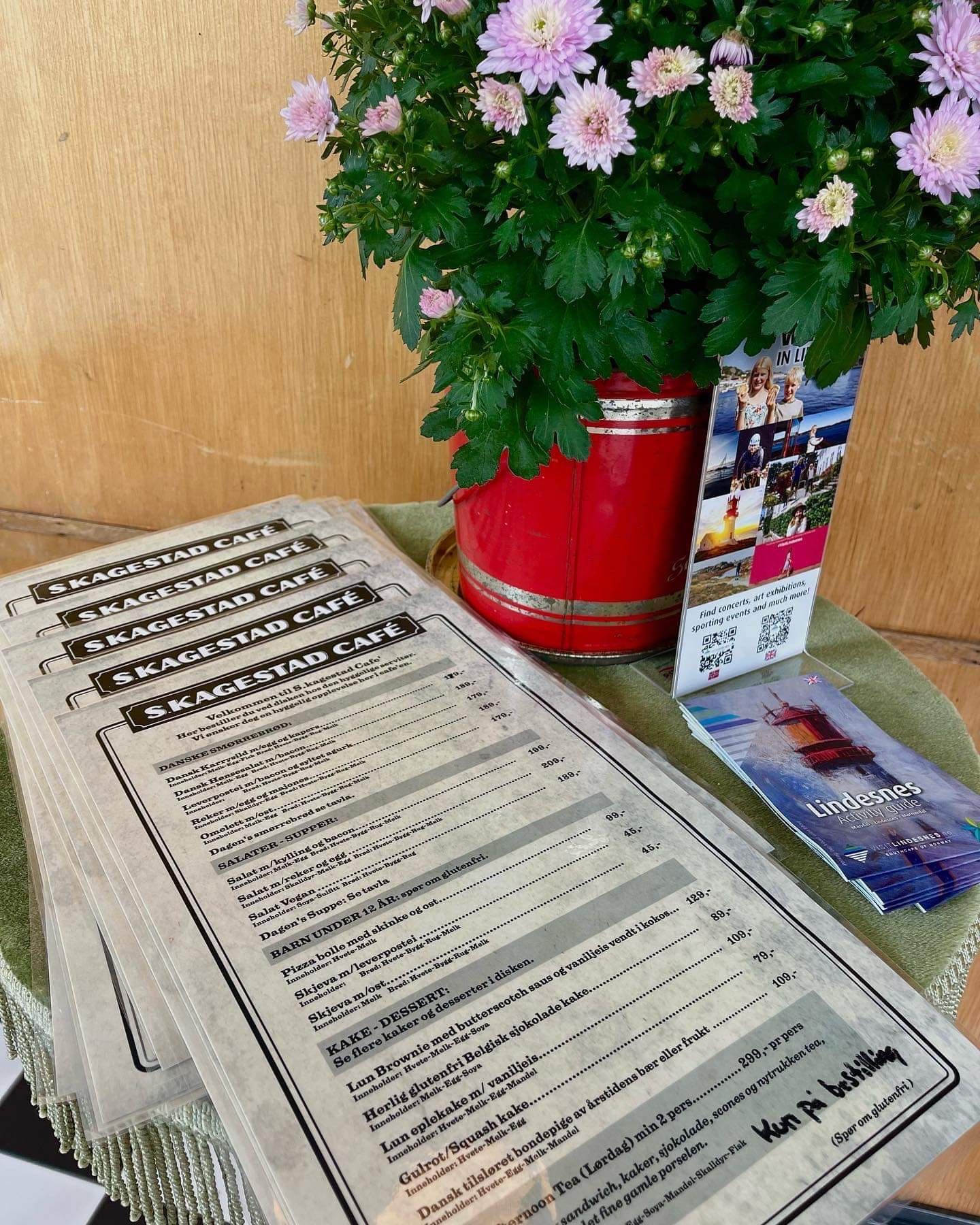 Bord i kafeen, hvor det står blomster til pynt og kafeens menyer ligger i en bunke