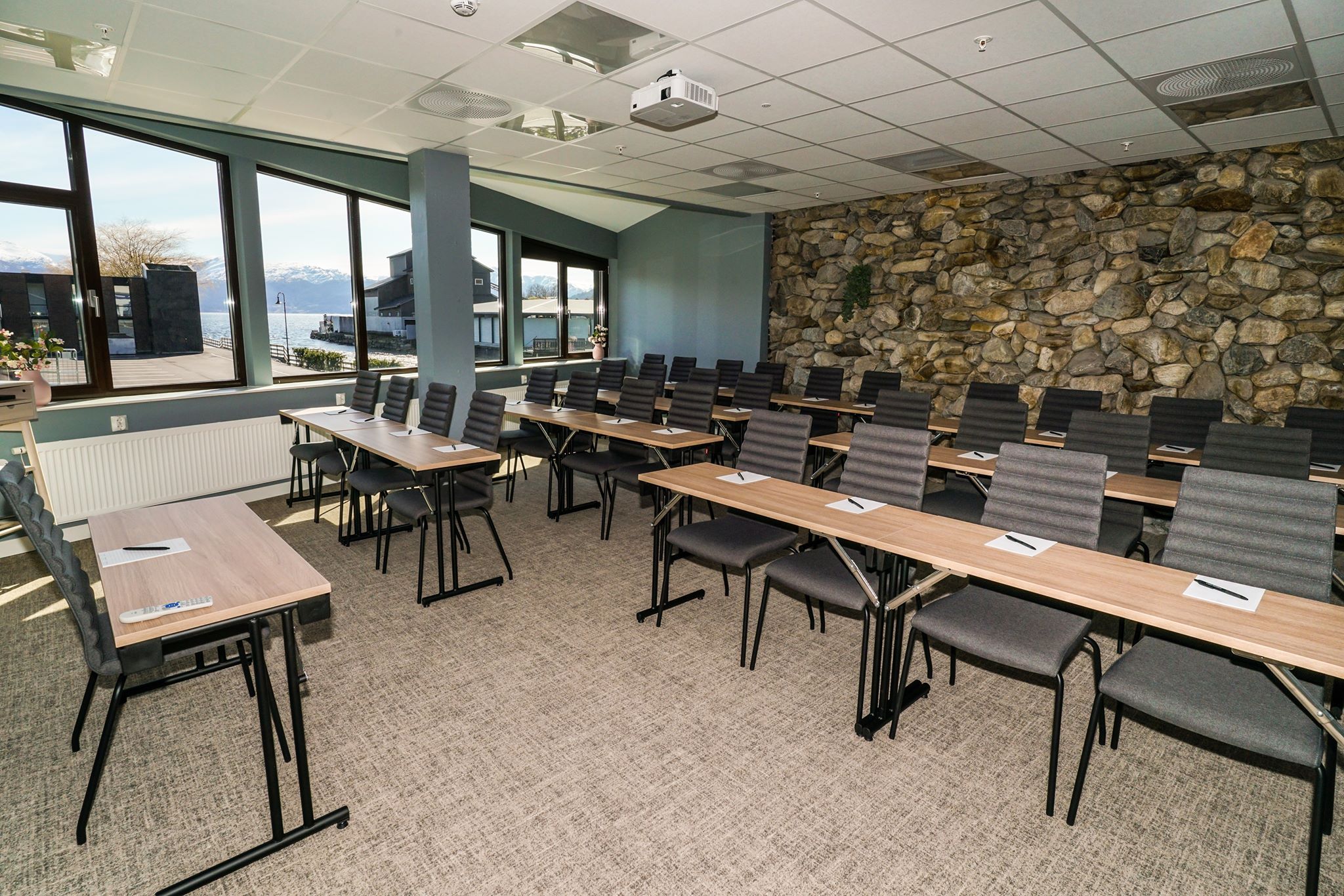 Meeting room with large windows and a natural stone wall.