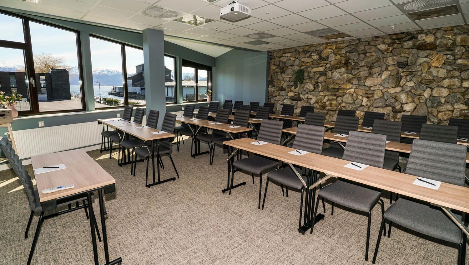 Meeting room with large windows and a natural stone wall.