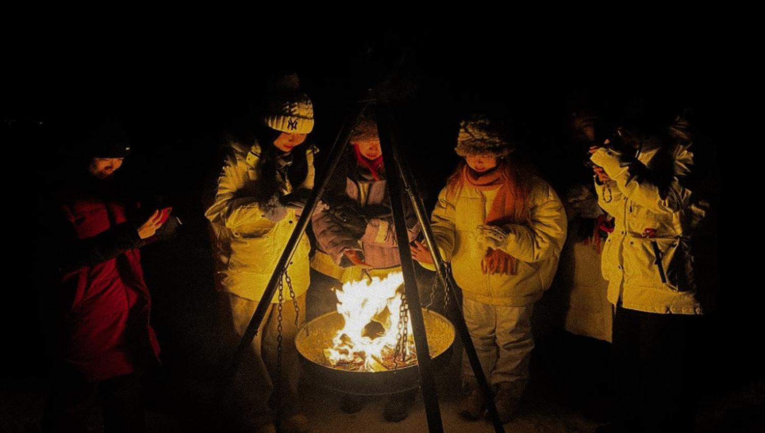 A group of guests sitting around a bonfire