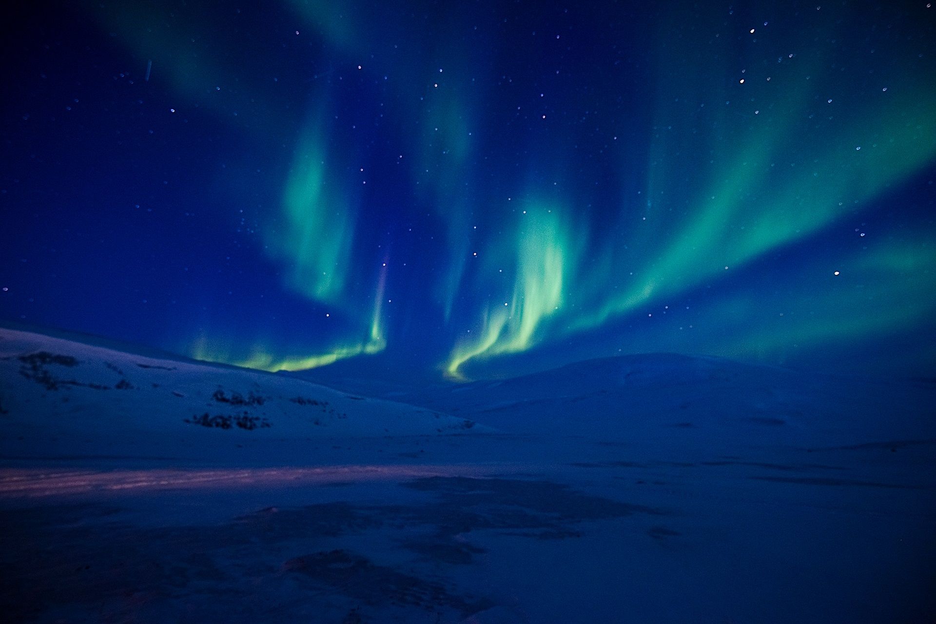 Nordlys som skinner på himmelen over fjell