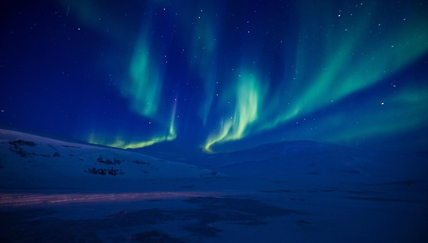Nordlys som skinner på himmelen over fjell