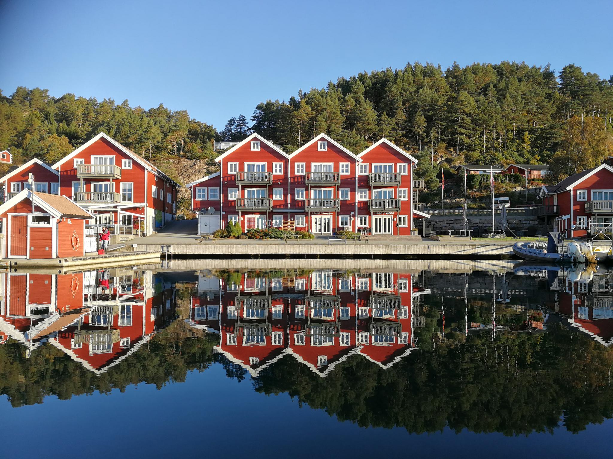 Tregde Ferie, photo taken from the water facing the dock, red buildings with white trim