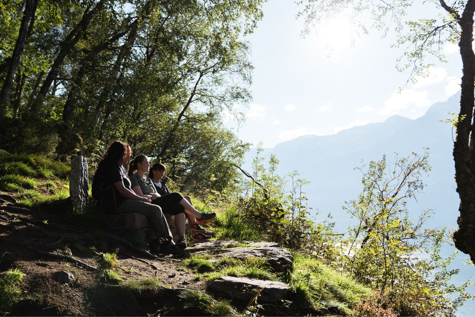 Three women sitting on a bench in the forest