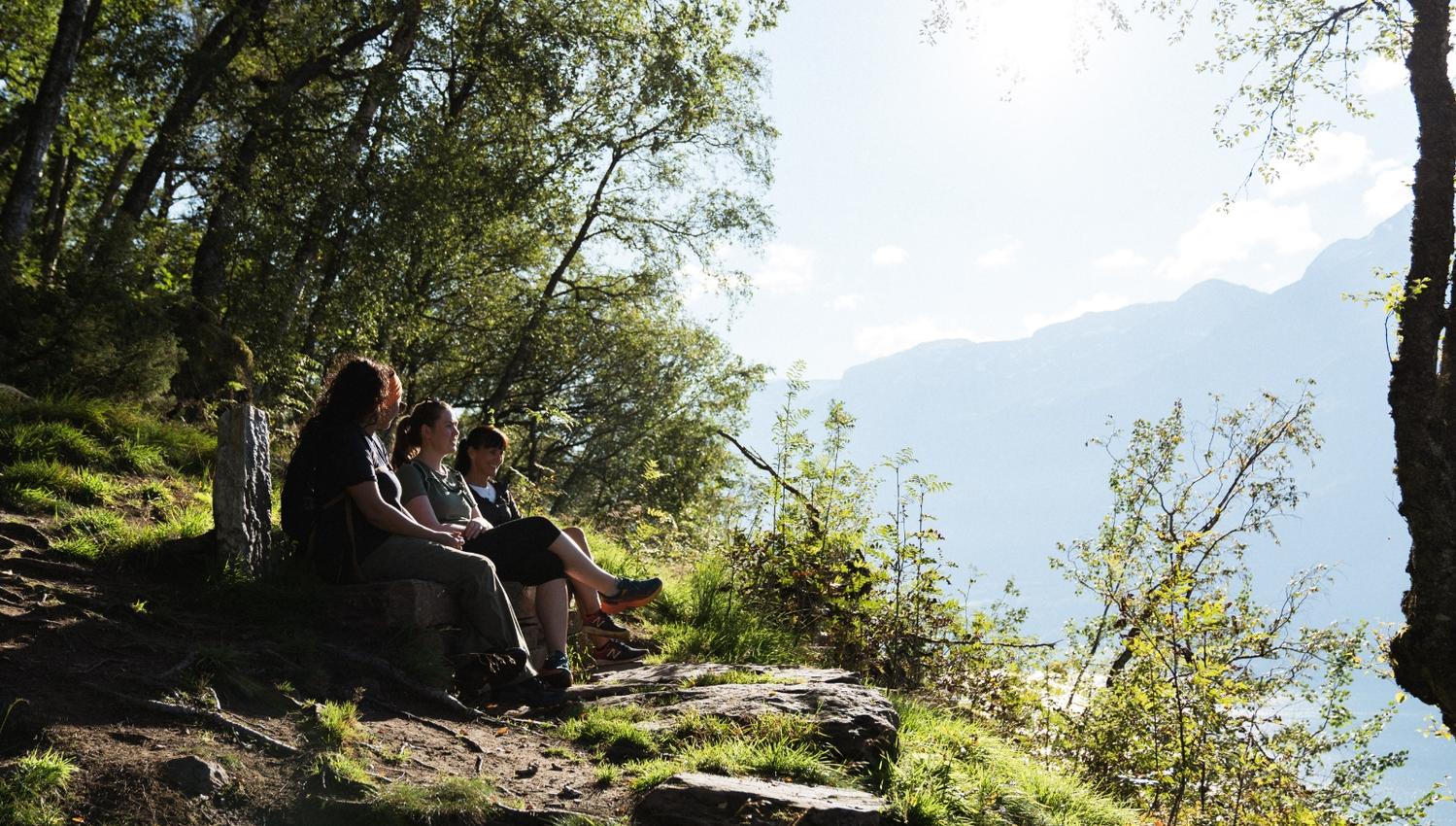 Three women sitting on a bench in the forest