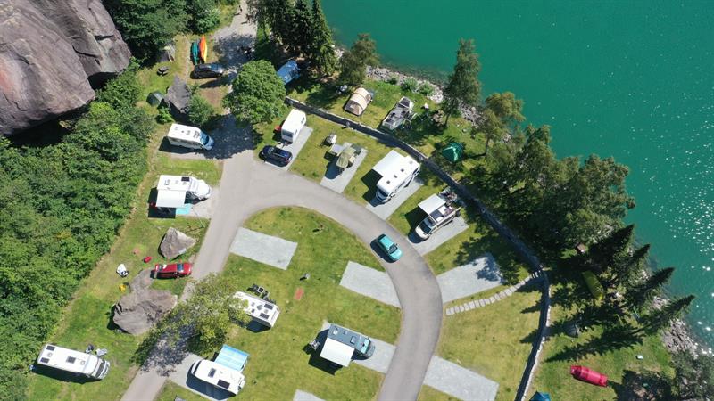Aerial view of Trolltunga Camping with motorhomes and tents by the turquoise lakeshore.