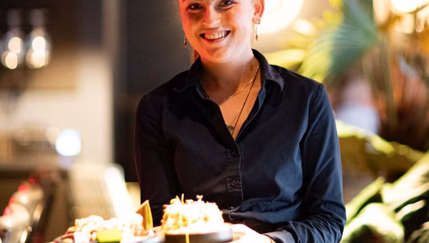 Female waitress carrying a tray of food