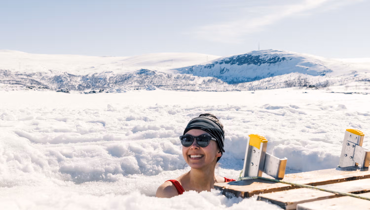 A woman enjoying an ice bath with a snow-covered landscape behind her.
