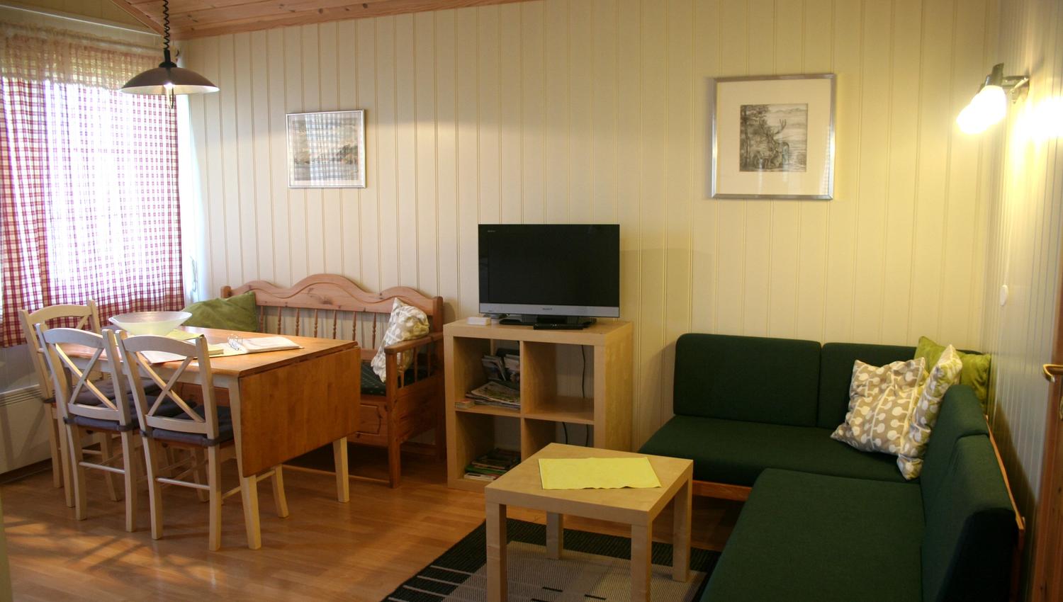 Bright and cozy living room with dining table, sofa, and TV at Oddland Camping in Hardanger.