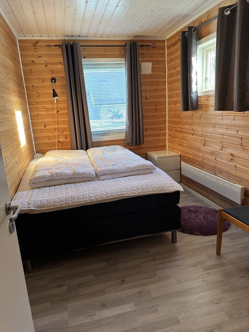 A bedroom with a double bed and wooden walls