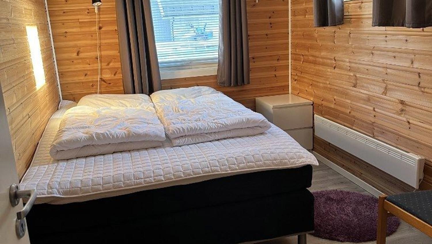 A bedroom with a double bed and wooden walls