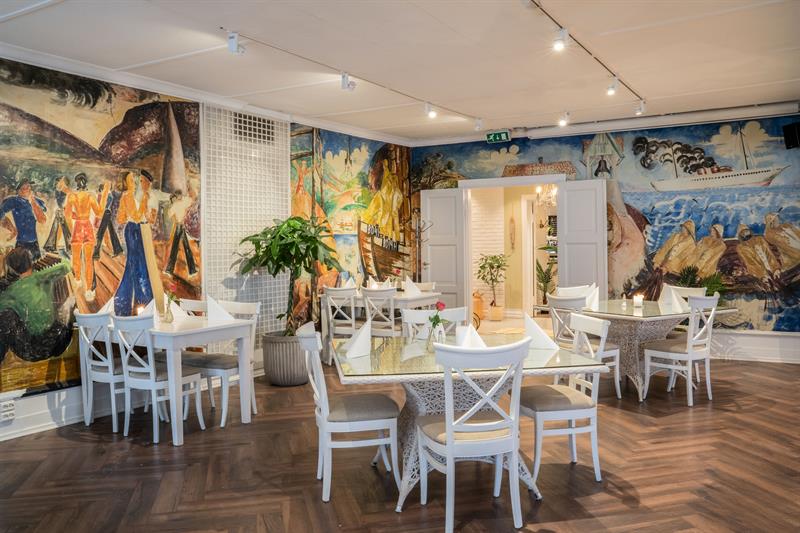 Tables an chairs in a room decorated with colourful frescoes on the walls