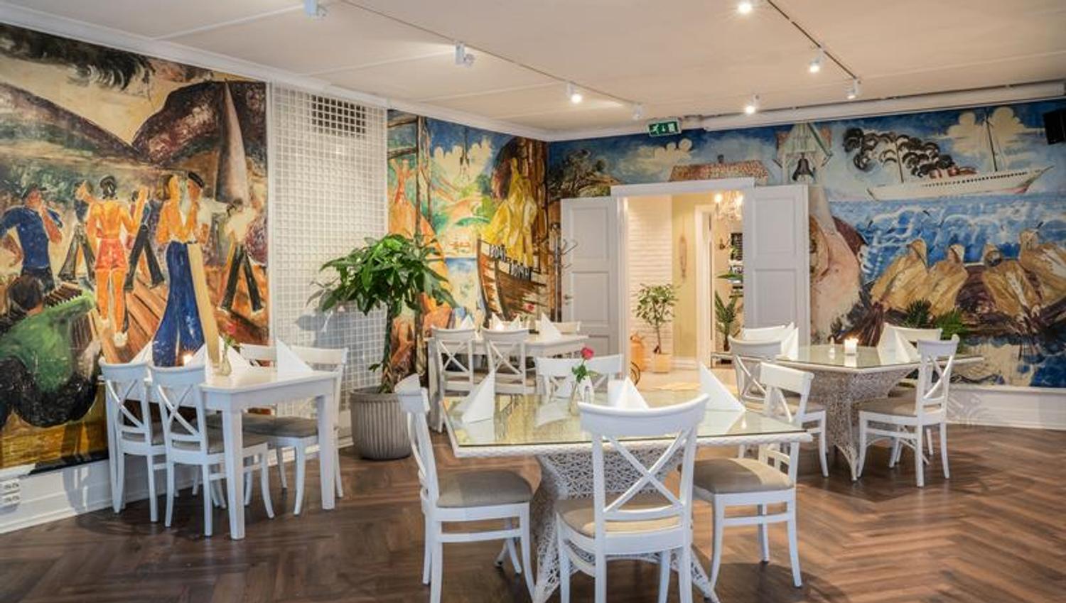 Tables an chairs in a room decorated with colourful frescoes on the walls