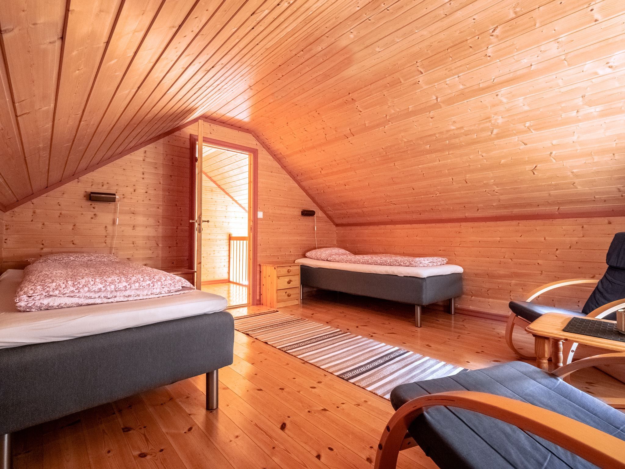 Cosy attic bedroom with two single beds, wooden floor, and slanted wooden ceiling