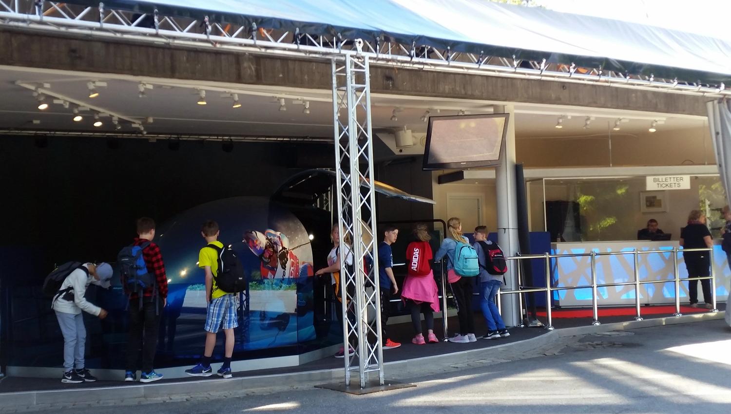 a crowd standing around the ski simulator