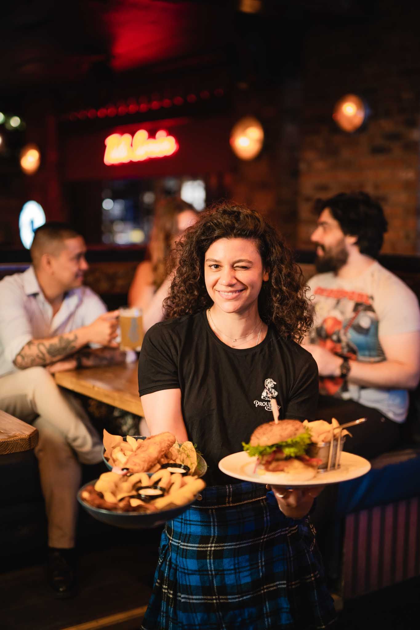 Waitress holding three dishes and winking at the photographer