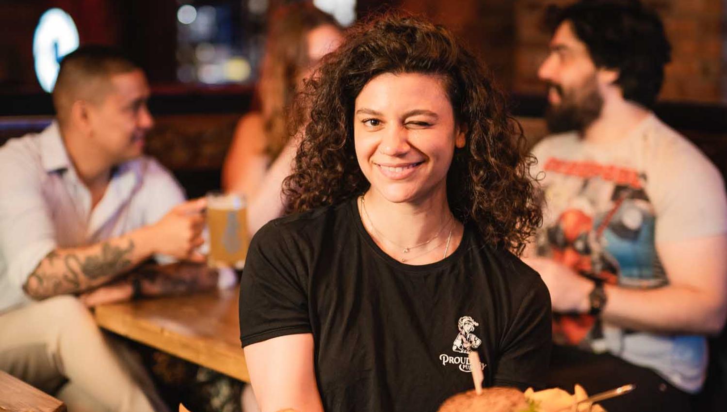 Waitress holding three dishes and winking at the photographer