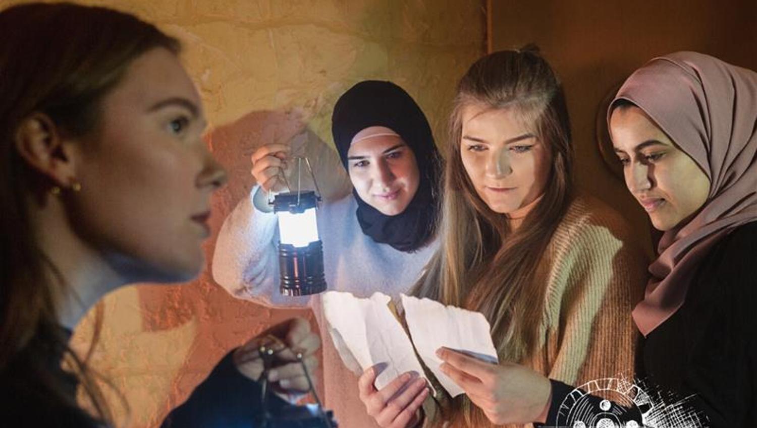 a group of women with lanterns in their hands read something written on two sheets of paper
