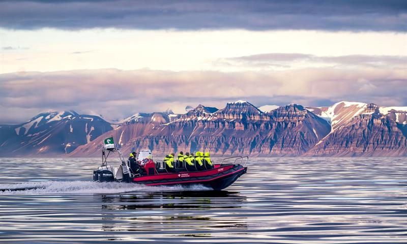 Åpen RIB båt på åpen fjord med fjell i bakgrunnen