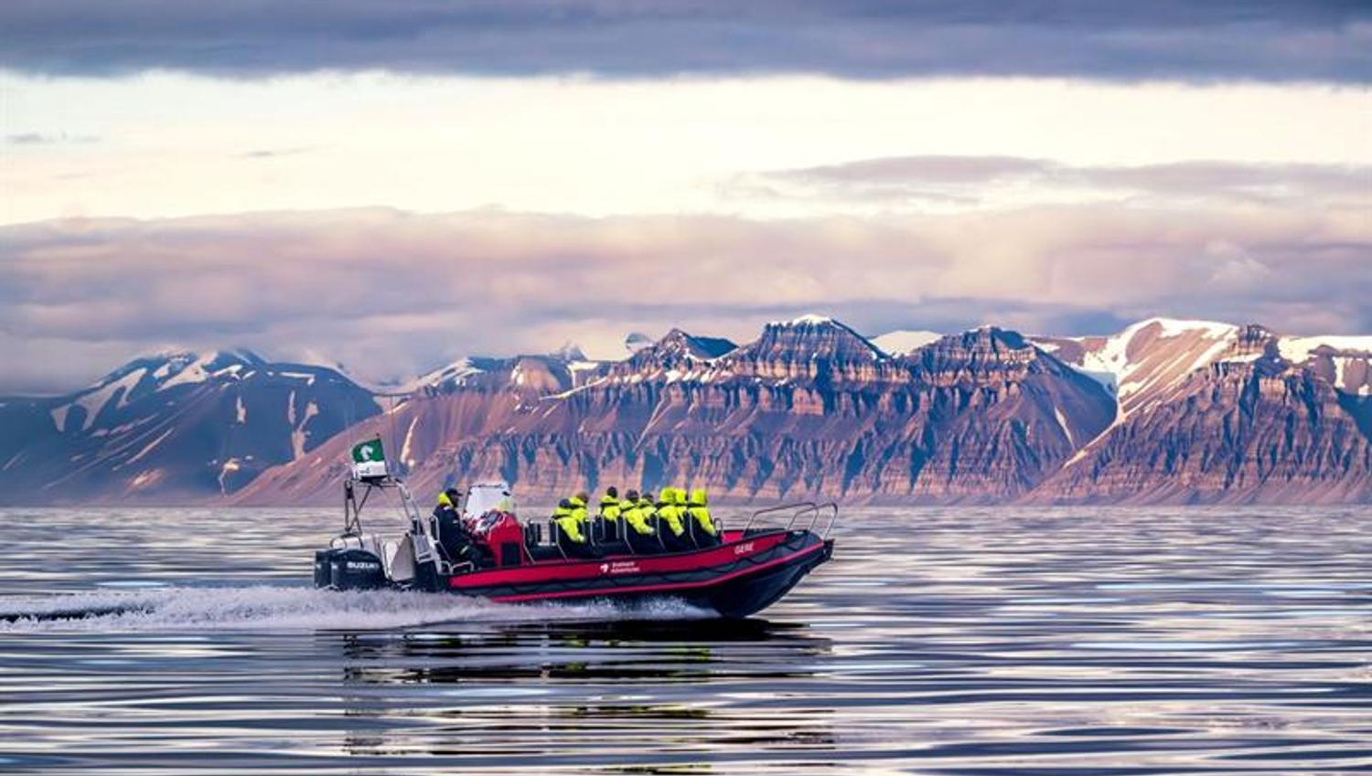 Åpen RIB båt på åpen fjord med fjell i bakgrunnen