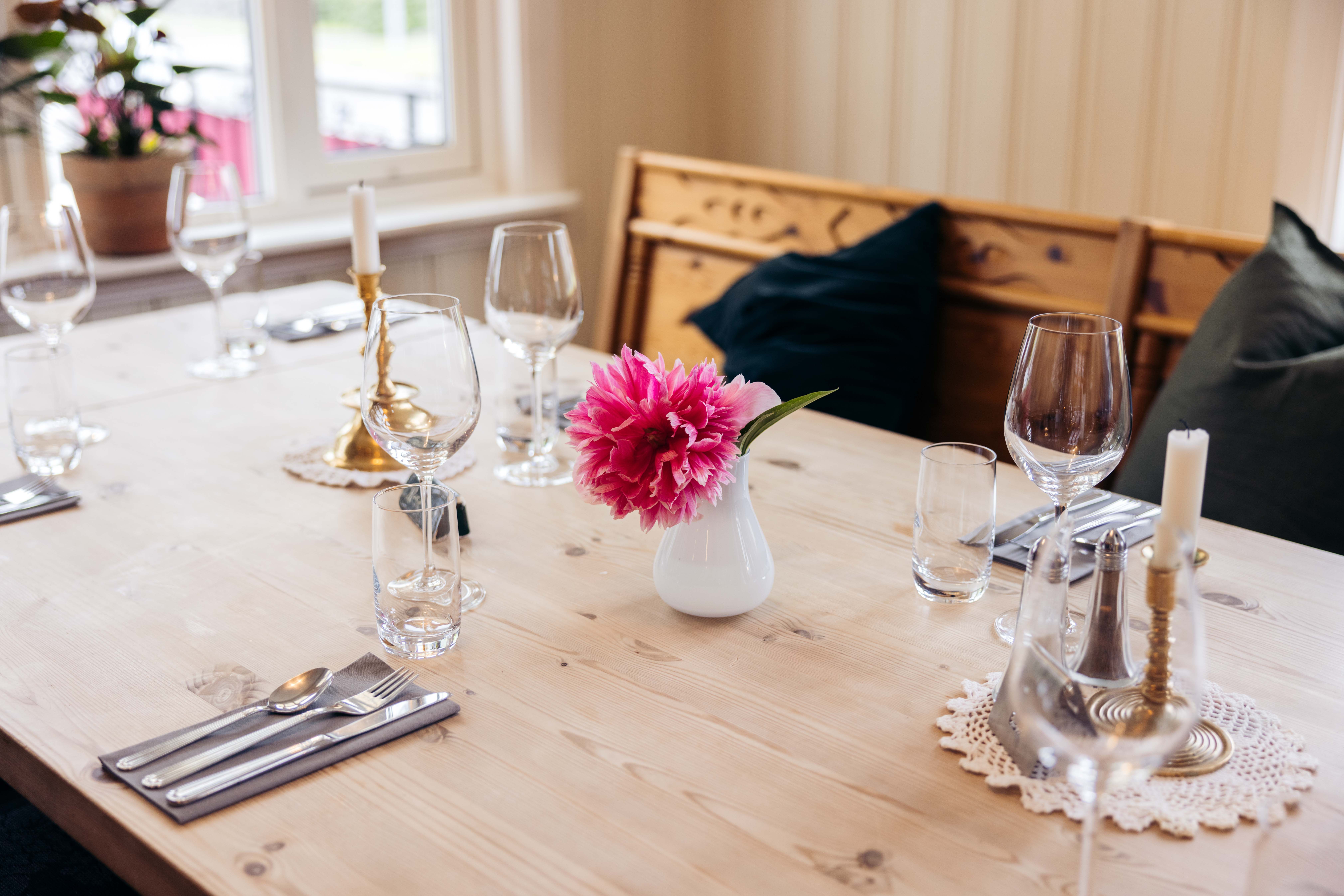 A table with a pink flower in a vase.
