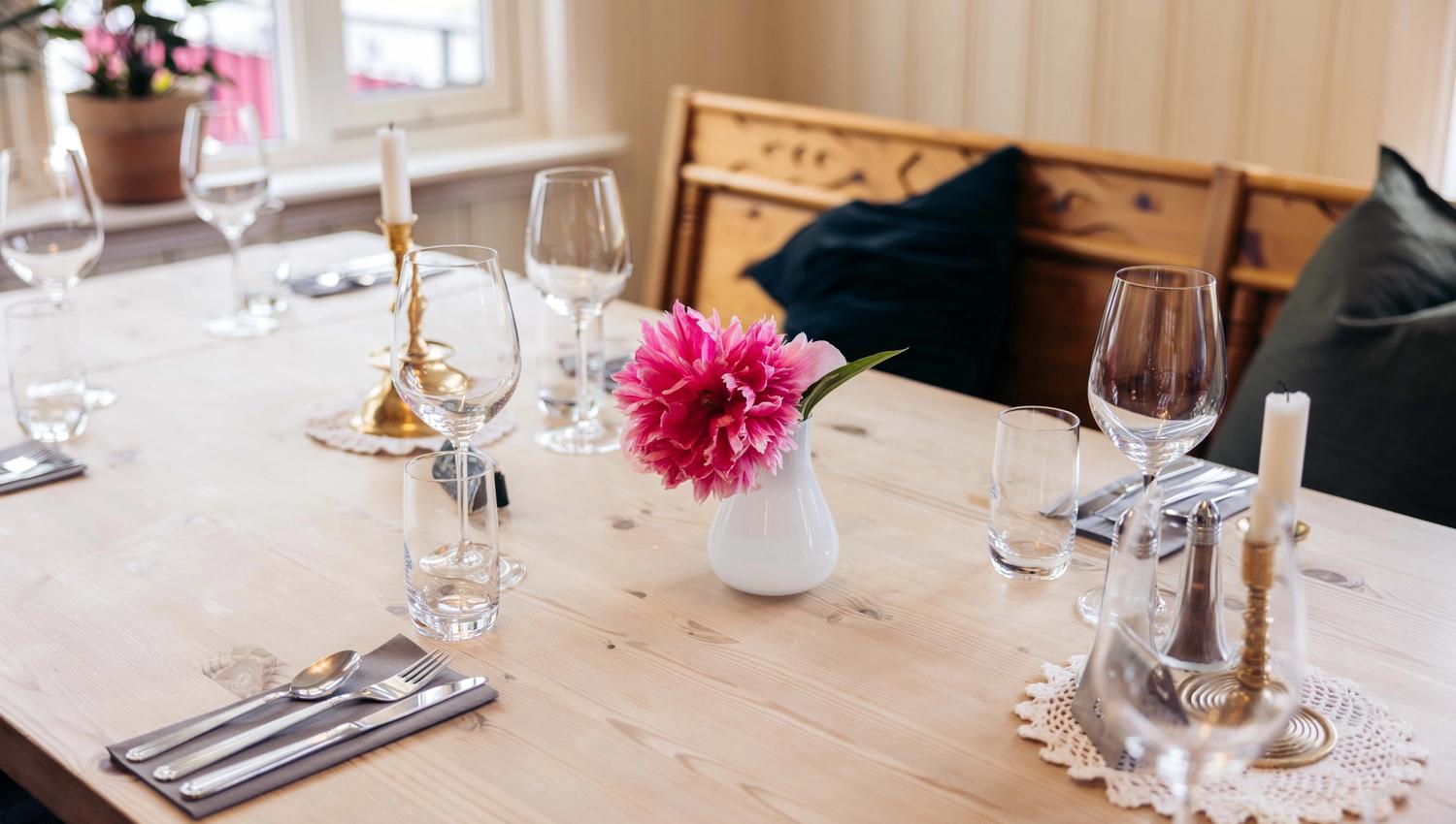 A table with a pink flower in a vase.