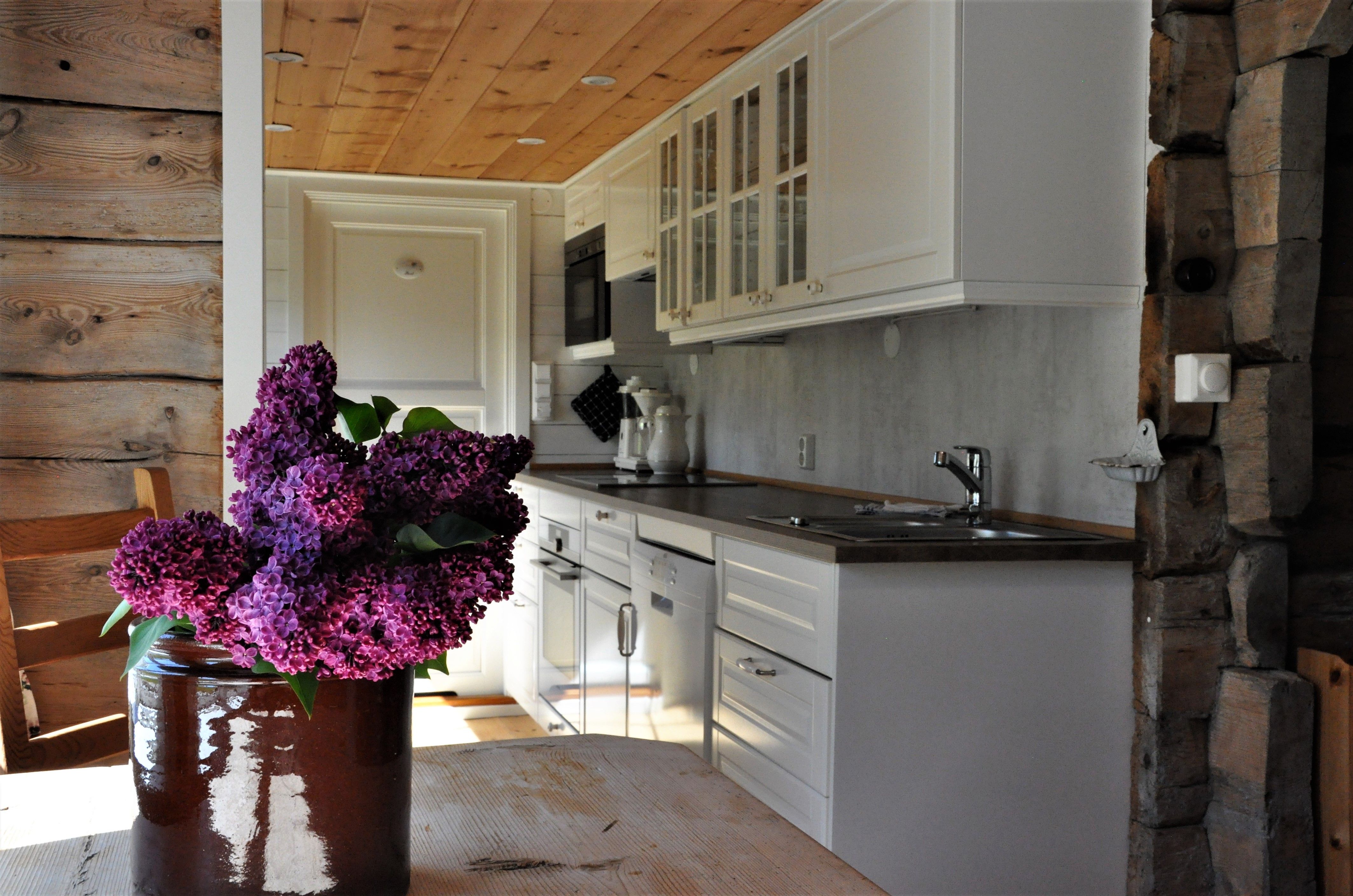 A white large kitchen with flowers in the foreground 
