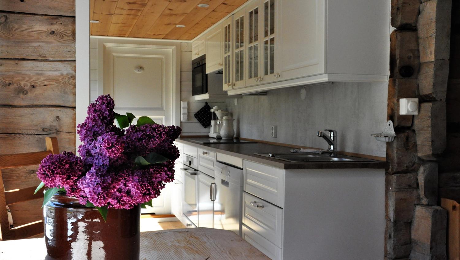A white large kitchen with flowers in the foreground