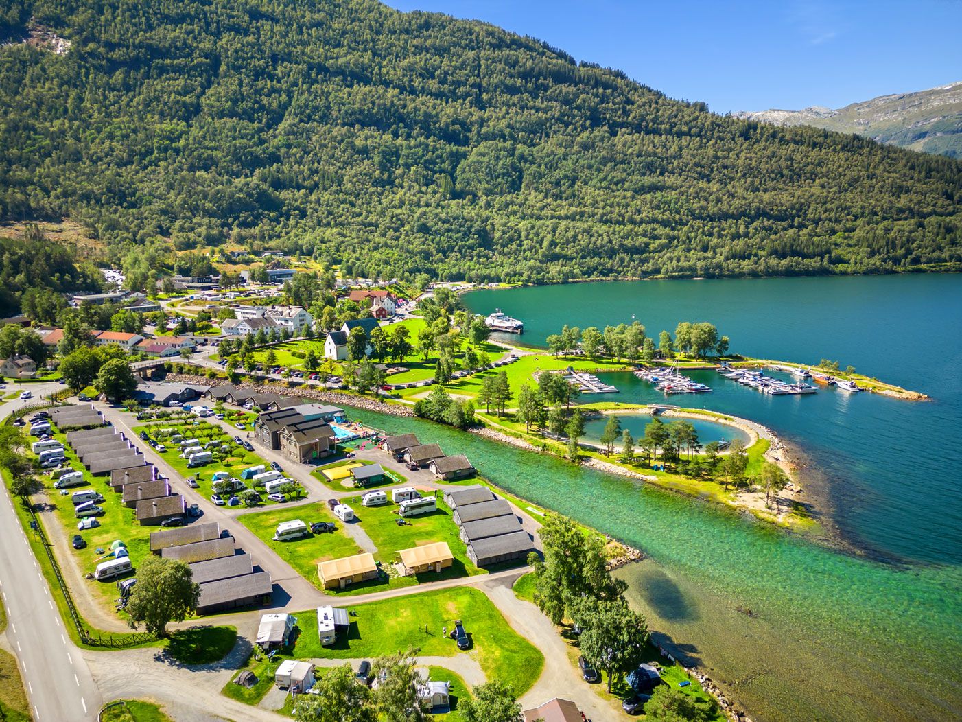 Luftaufnahme von Mikkelparken Ferietun mit Campingbereich, Hütten und atemberaubender Aussicht auf den Fjord und die Berge.
