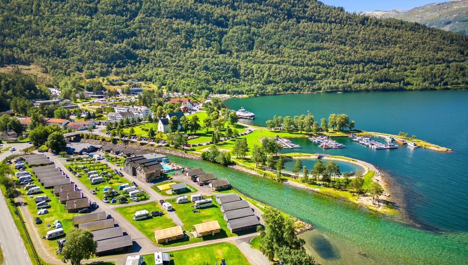 Luftaufnahme von Mikkelparken Ferietun mit Campingbereich, Hütten und atemberaubender Aussicht auf den Fjord und die Berge.