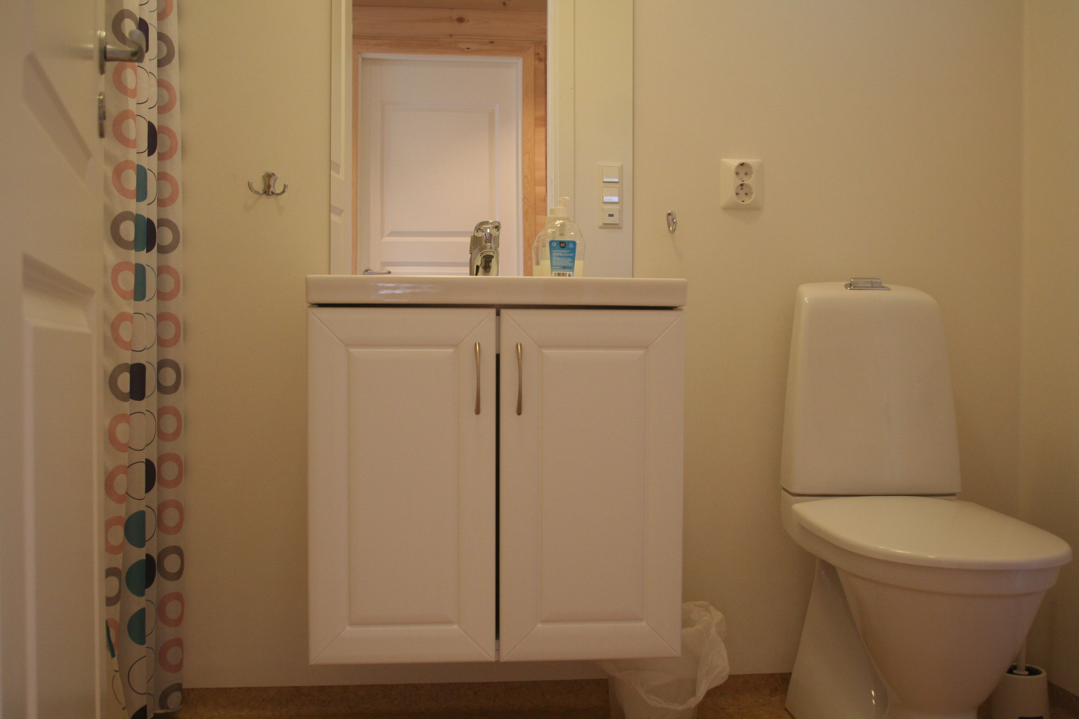 Clean and modern bathroom with sink, mirror and toilet at Vågen Rooms and Cabins.