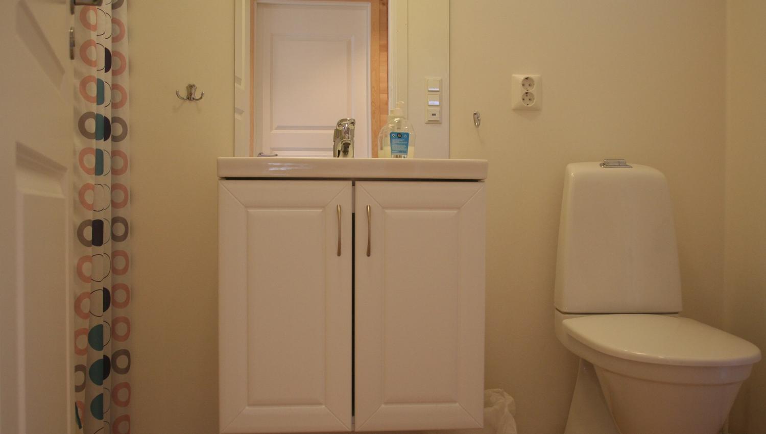 Clean and modern bathroom with sink, mirror and toilet at Vågen Rooms and Cabins.