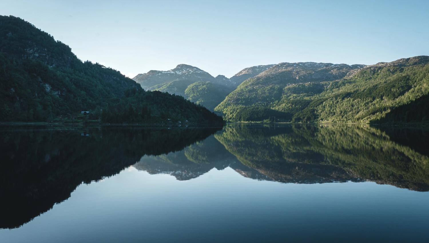 Mirror-calm lake reflecting the surrounding mountains in Hardanger.