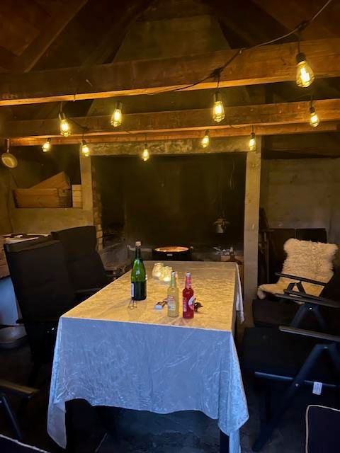 Cozy indoor fireplace room at Jaastad Gjestetun with string lights, a set table, and a rustic atmosphere. Ideal for gatherings.