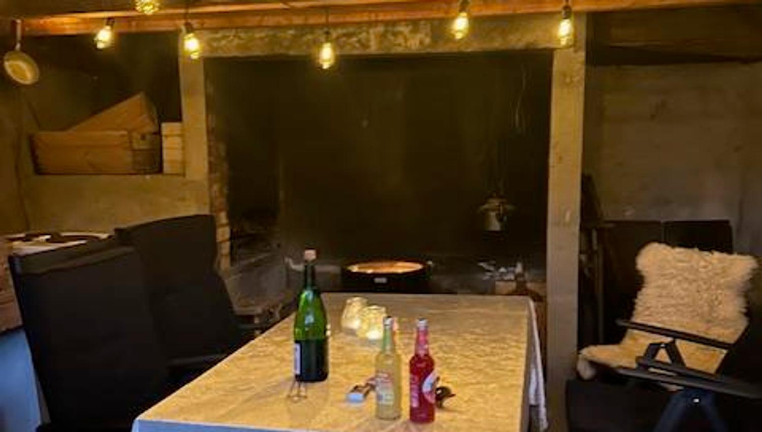 Cozy indoor fireplace room at Jaastad Gjestetun with string lights, a set table, and a rustic atmosphere. Ideal for gatherings.