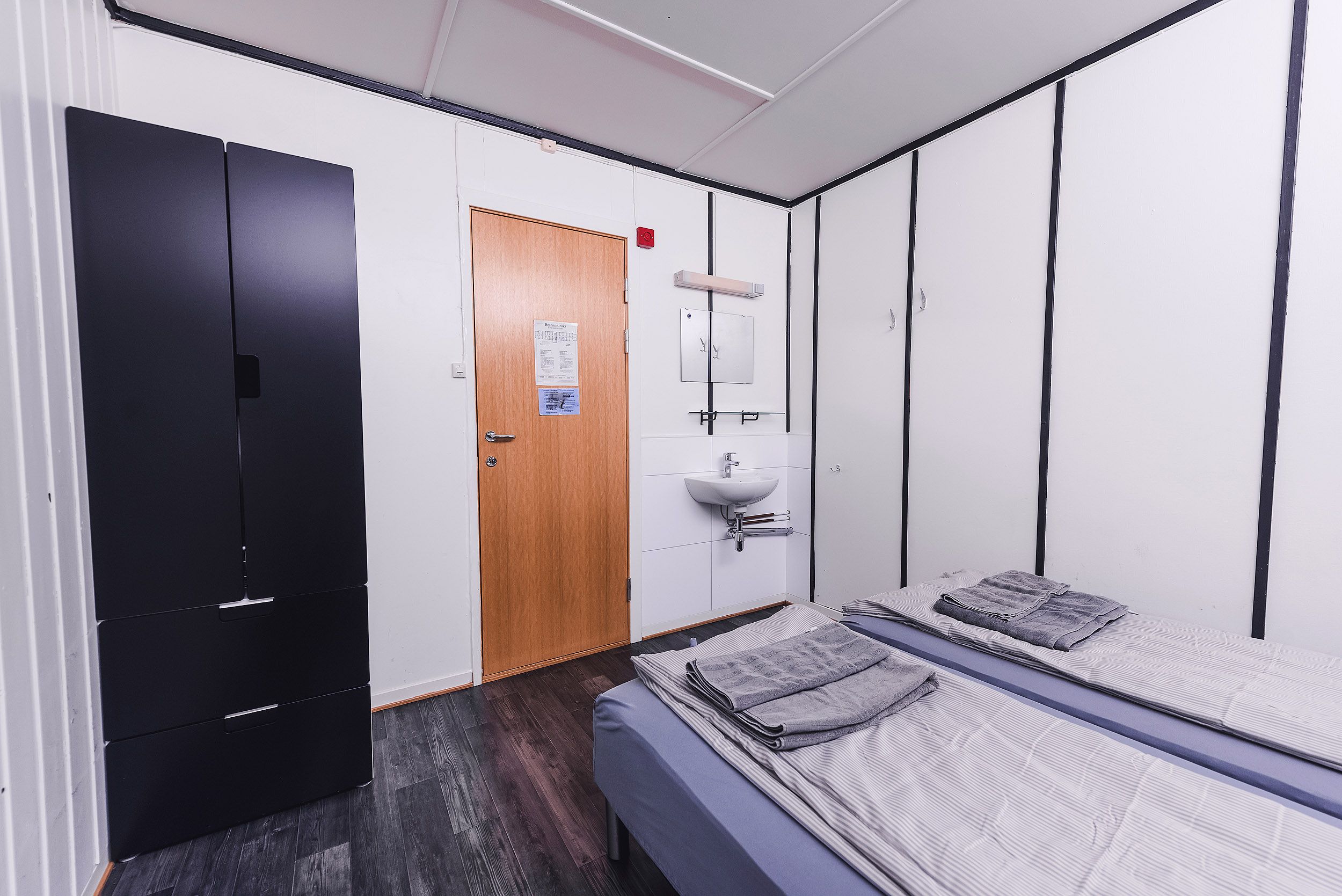 A bedroom with two beds, a closet and a sink.